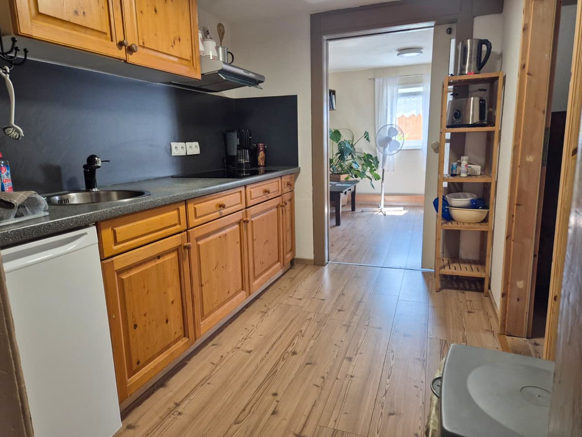 Küche der kleinen Ferienwohnung mit Holzschränken und Blick zum Wohnbereich